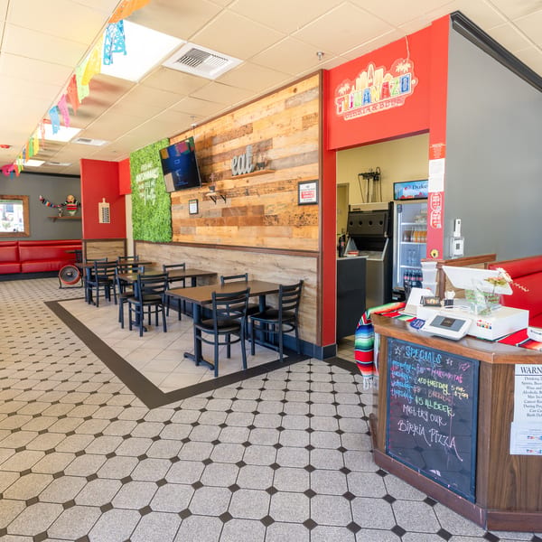 Interior of a vibrant Mexican restaurant with colorful decor, red booths, and wooden tables.